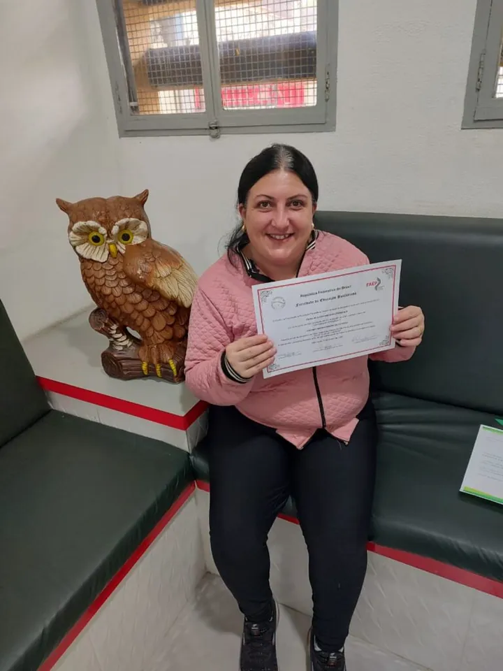 Aluna formada segurando seu certificado na sede